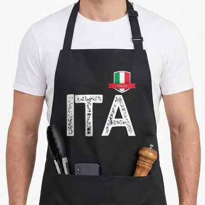 Tablier de cuisine noir avec les lettres ITA en blanc texturé et un écusson au drapeau italien portant l'inscription ITALIA.