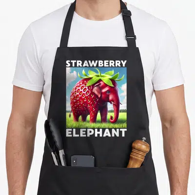 Tablier de cuisine noir avec une illustration d'un éléphant rouge en forme de fraise sous un ciel bleu.