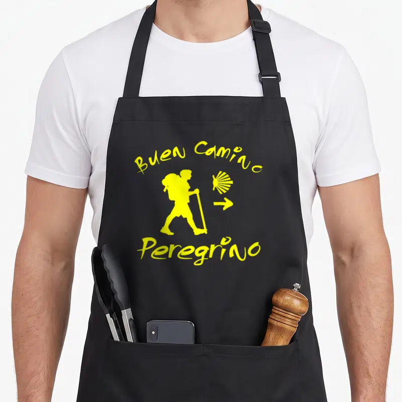 Tablier de cuisine noir avec silhouette jaune d'un pèlerin, une coquille et le texte Buen Camino Peregrino.