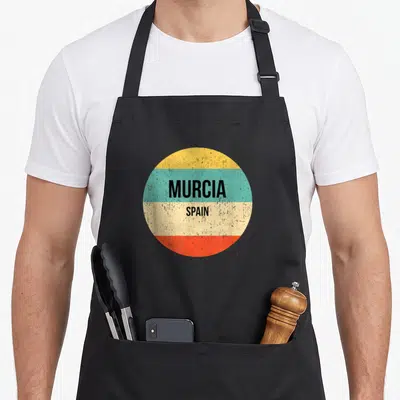 Tablier de cuisine noir avec un motif circulaire coloré affichant Murcia Spain en lettres noires sur fond strié vintage.