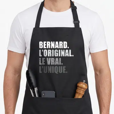 Tablier de cuisine noir avec inscription typographique blanche et grise proclamant Bernard l'original le vrai unique.