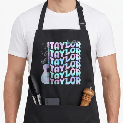 Tablier de cuisine noir avec motif Taylor en dégradé pastel, guitare acoustique et notes de musique flottantes.