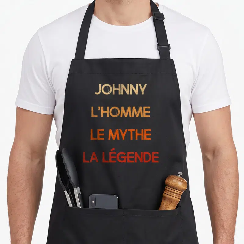 Tablier de cuisine noir avec inscription Johnny l'homme le mythe la légende en lettres dégradées orange et rouge.
