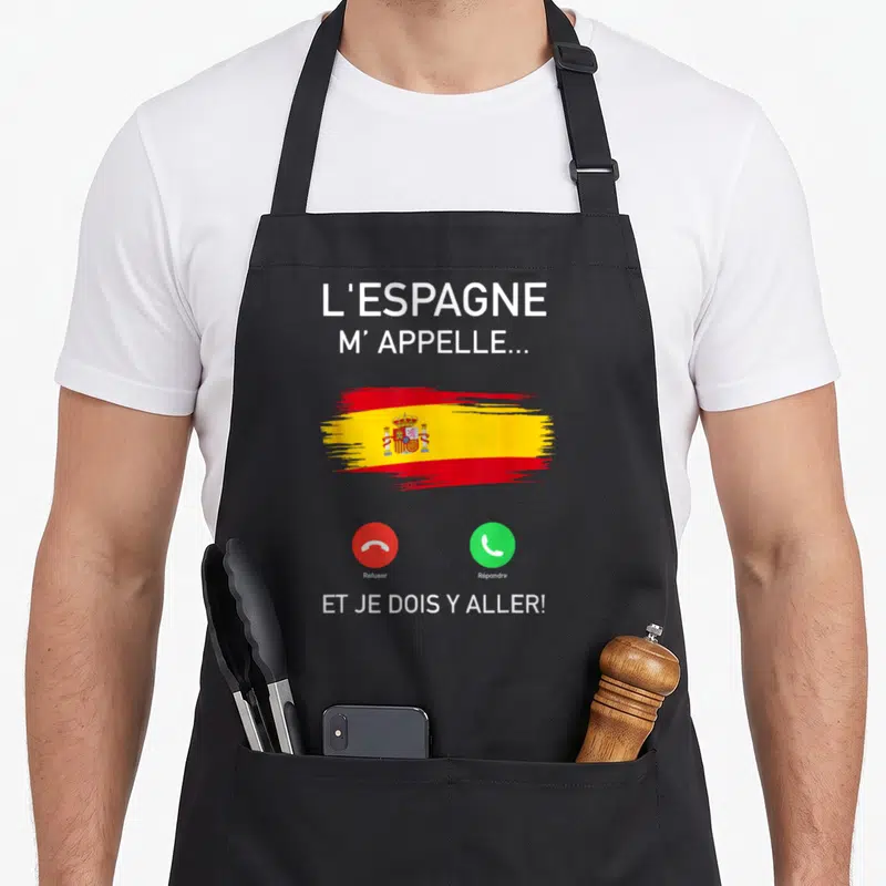 Tablier de cuisine noir avec l'Espagne m'appelle et je dois y aller imprimé en blanc sur fond gris.
