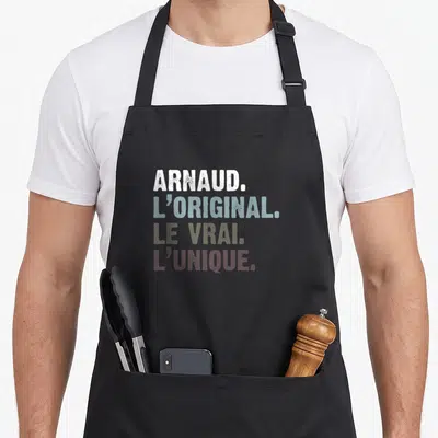 Tablier de cuisine noir avec Arnaud l'original le vrai l'unique en lettres colorées superposées.