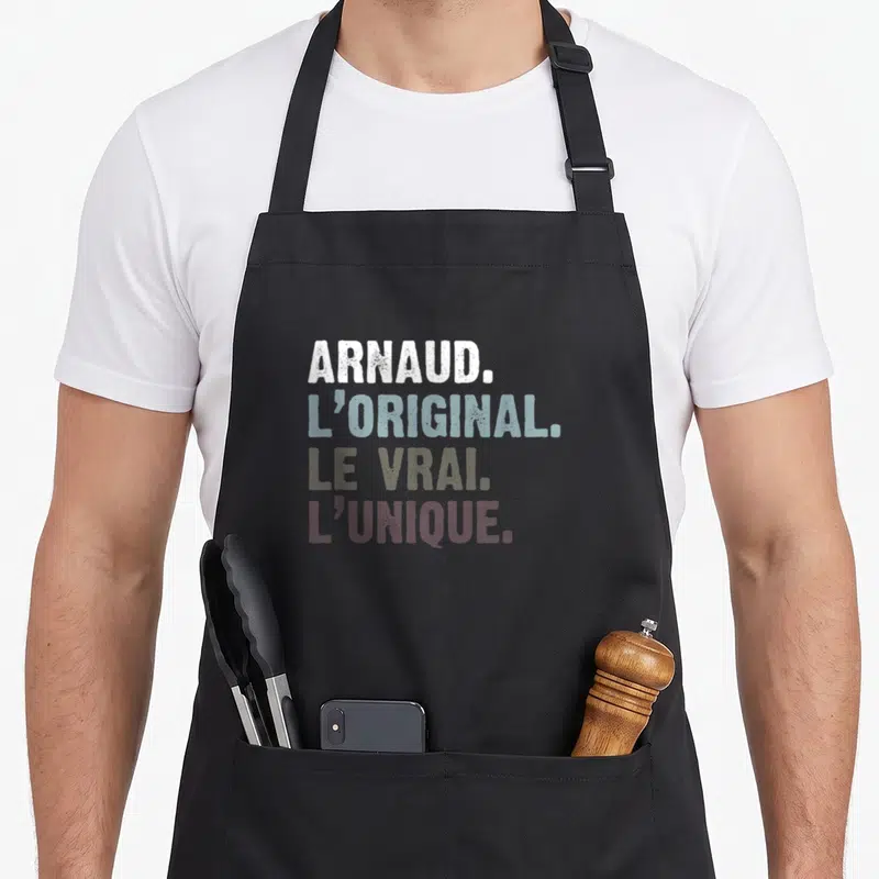 Tablier de cuisine noir avec Arnaud l'original le vrai l'unique en lettres colorées superposées.