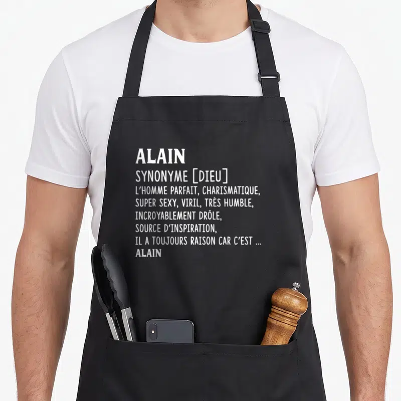 Tablier de cuisine noir avec le texte blancnant Alain comme un synonyme de dieu et l'homme parfait.
