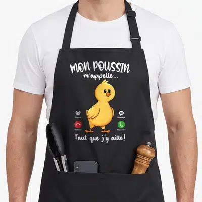Tablier de cuisine noir avec illustration poussin jaune et texte Mon Poussin m'appelle Faut que j'y aille sur fond gris uni.