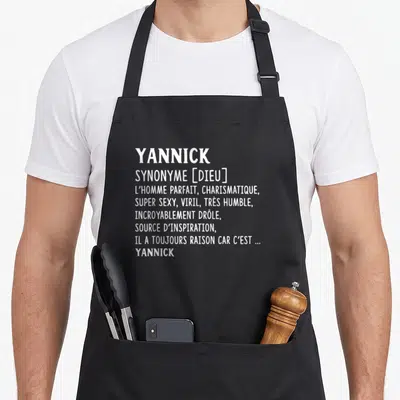 Tablier de cuisine noir avec texte blanc définissant Yannick comme un synonyme de dieu et d'homme parfait.