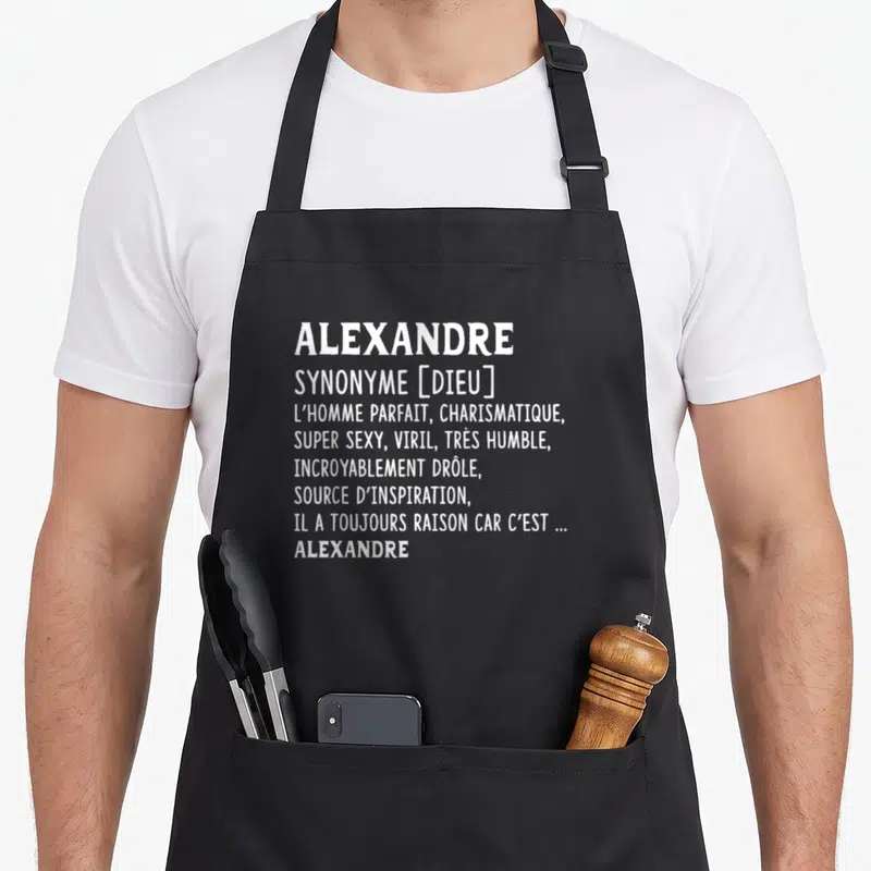 Tablier de cuisine noir avec le prénom Alexandre et sa définition humoristique en lettres blanches.