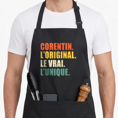 Tablier de cuisine noir avec le texte Corentin l'original le vrai l'unique en lettres colorées et style vieilli.