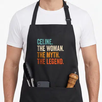 Tablier de cuisine noir avec le texte Celine The Woman The Myth The Legend en lettres capitales multicolores.
