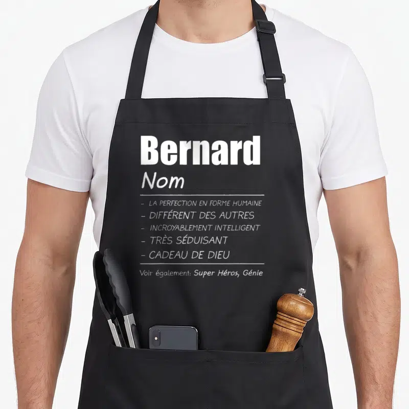 Tablier de cuisine noir avec le prénom Bernard et des qualificatifs humoristiques imprimés en typographie blanche contrastante sur le devant.