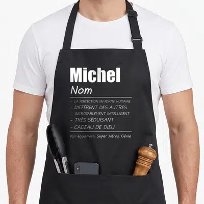 Tablier de cuisine noir avec le nom Michel et une liste d'attributs humoristiques en typographie blanche sur fond uni.