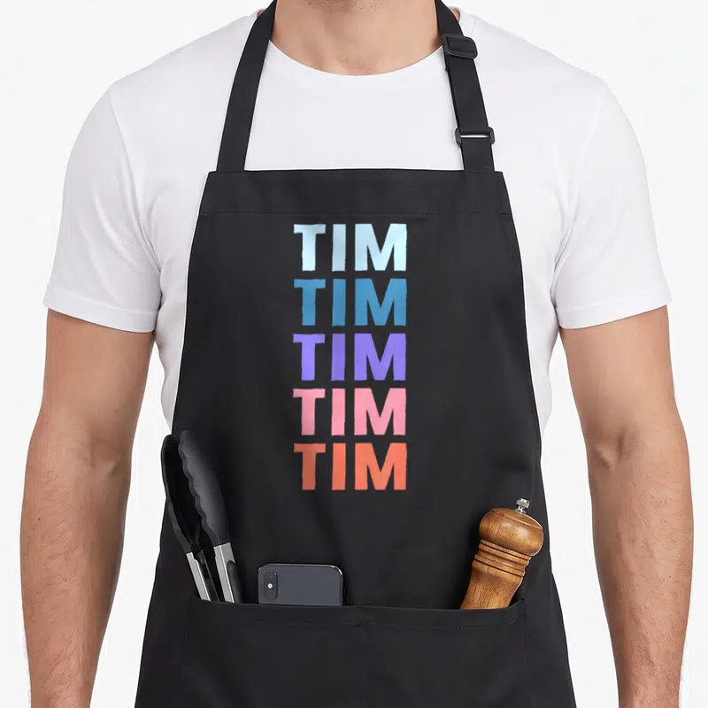 Tablier de cuisine noir avec le prénom Tim répété cinq fois en lettres colorées verticales.