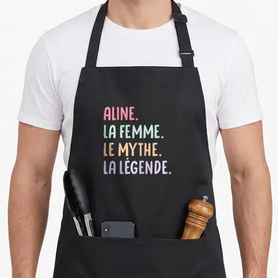 Tablier de cuisine noir avec Aline la femme le mythe la légende en lettres pastel.