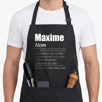 Tablier de cuisine noir avec le nom Maxime et la liste des qualités La perfection en forme humaine et Cadeau de Dieu.