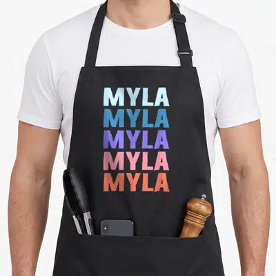 Tablier de cuisine noir avec le prénom Myla répété cinq fois en lettres majuscules colorées de bleu à orange.