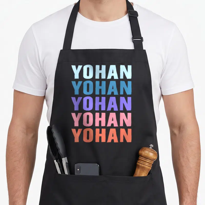 Tablier de cuisine noir avec le prénom Yohan répété cinq fois en lettres majuscules colorées de bleu, violet, rose et orange.