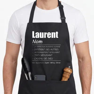 Tablier de cuisine noir avec le nom Laurent et une liste de qualificatifs humoristiques en typographie blanche sur fond uni.