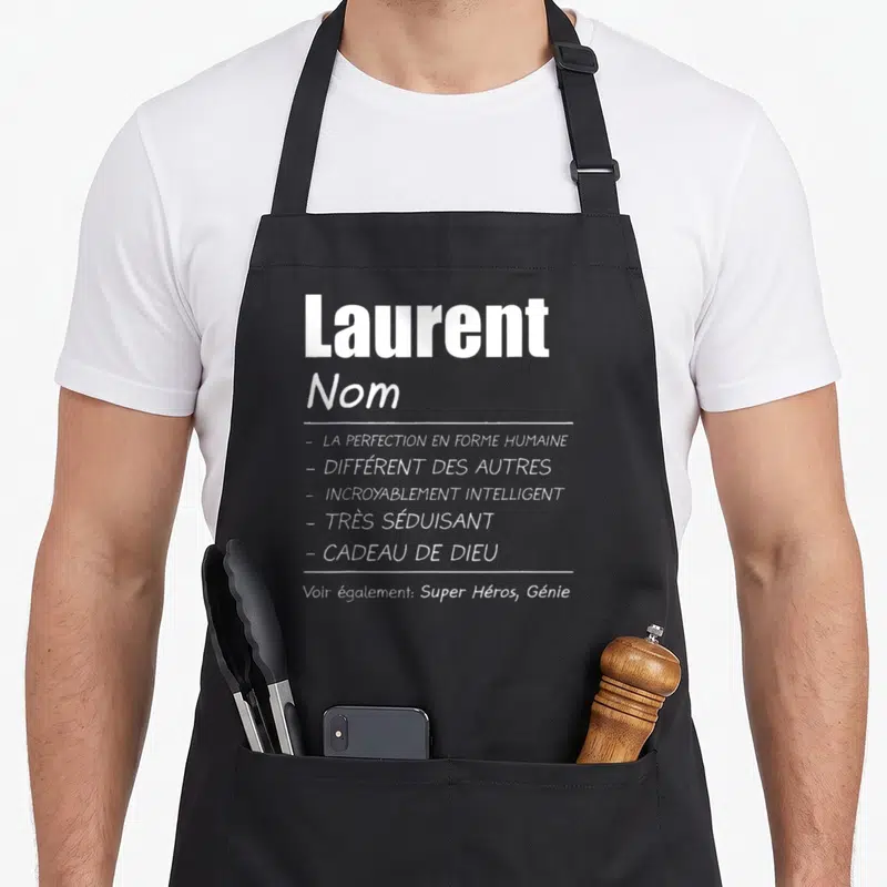 Tablier de cuisine noir avec le nom Laurent et une liste de qualificatifs humoristiques en typographie blanche sur fond uni.