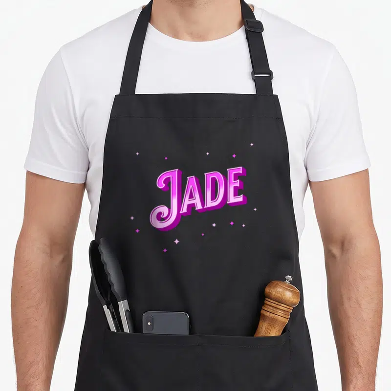 Tablier de cuisine noir avec le nom Jade en lettres roses 3D entouré d'étoiles scintillantes.