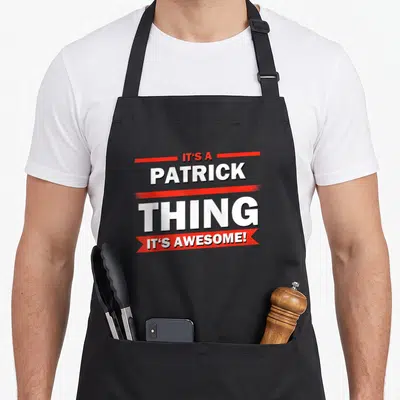 Tablier de cuisine noir avec l'inscription It's a Patrick Thing C'est Génial en blanc et rouge.