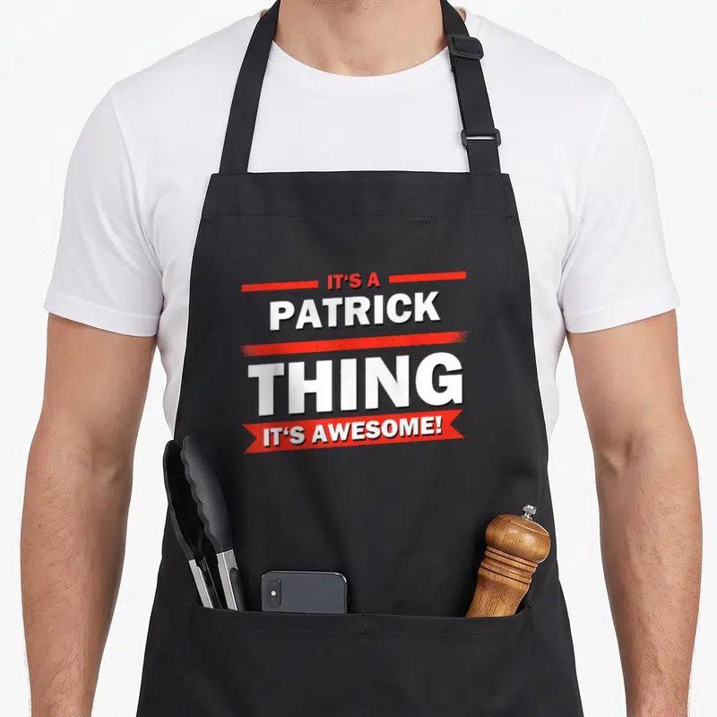 Tablier de cuisine noir avec l'inscription It's a Patrick Thing C'est Génial en blanc et rouge.