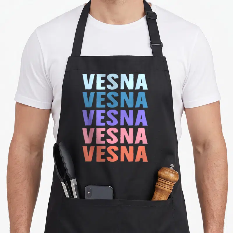 Tablier de cuisine noir avec le prénom Vesna imprimé cinq fois en lettres majuscules colorées de bleu à orange.