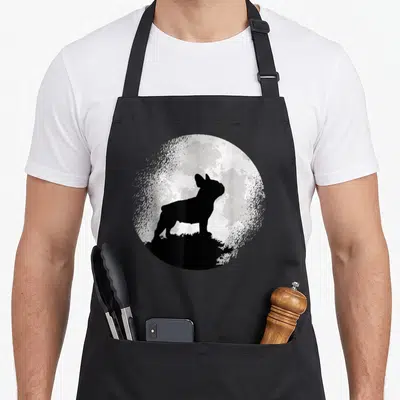 Tablier de cuisine noir avec silhouette de bouledogue français devant une lune texturée en cercle.
