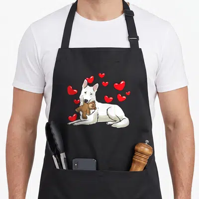 Tablier de cuisine noir avec illustration d'un chien blanc tenant un ours en peluche et des cœurs rouges flottants.