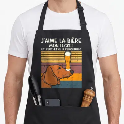 Tablier de cuisine noir avec illustration vintage d'un teckel orange tenant une bière sur le nez.