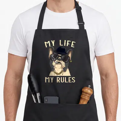 Tablier de cuisine noir avec illustration d'un bouledogue français coiffé d'un chapeau et portant des lunettes de soleil.