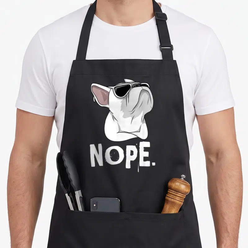 Tablier de cuisine noir avec illustration d'un Bouledogue français blanc portant des lunettes noires et le texte Nope.