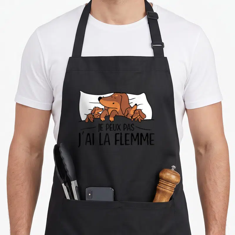 Tablier de cuisine noir avec un teckel et ses petits au lit sous la couverture, texte imprimé Je peux pas j'ai la flemme.