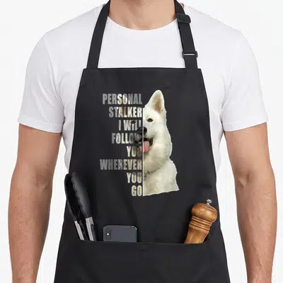 Tablier de cuisine noir avec portrait demi-partie d'un Berger blanc suisse et texte en anglais superposé.