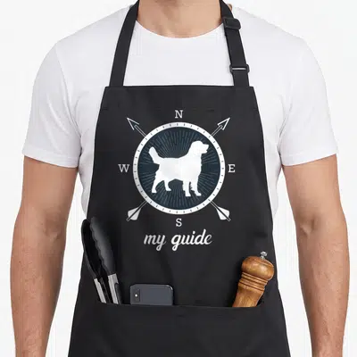 Tablier de cuisine noir avec silhouette de chien blanc sur boussole et texte my guide en bas.
