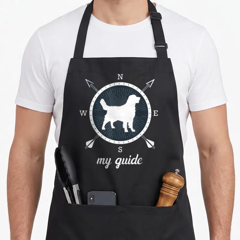 Tablier de cuisine noir avec silhouette de chien blanc sur boussole et texte my guide en bas.