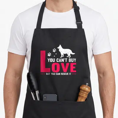 Tablier de cuisine noir avec silhouette chien blanc, traces de pattes et texte You Can Buy Love Rescue It rose et blanc.