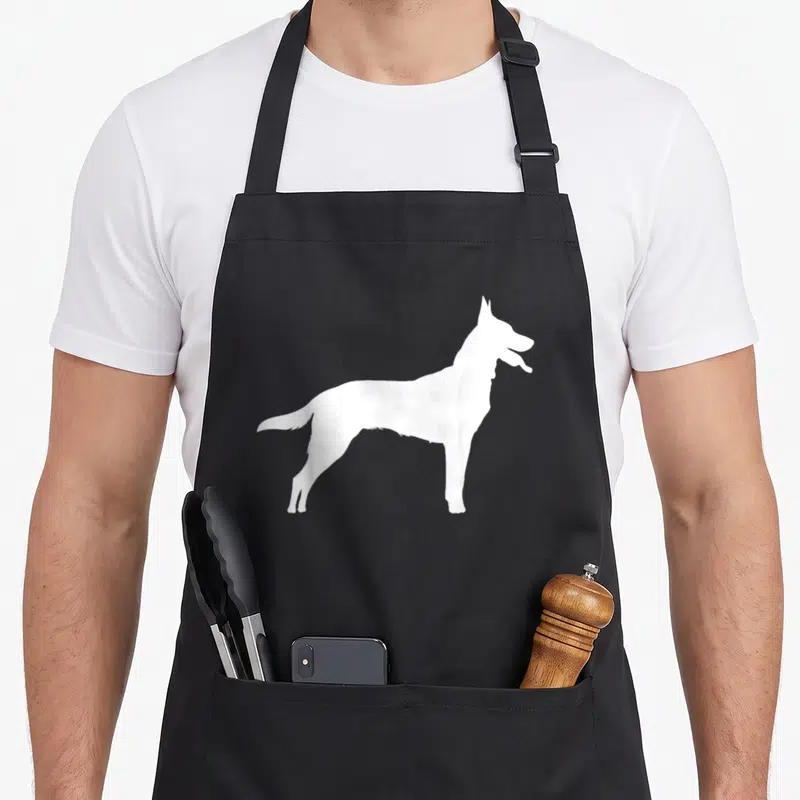 Tablier de cuisine noir avec silhouette blanche latérale d'un chien de type Berger Belge Malinois debout et regardant vers la droite.