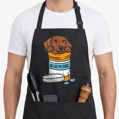 Tablier de cuisine noir avec illustration d'un teckel sortant d'un flacon Antidepressant orange et bleu.