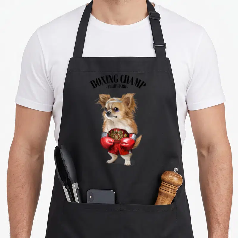 Tablier de cuisine noir avec un Chihuahua boxeur portant des gants rouges et une ceinture de champion.