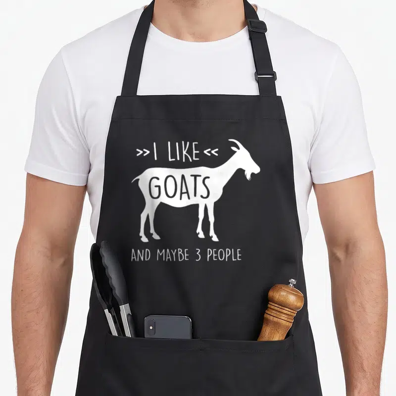 Tablier de cuisine noir avec silhouette blanche de chèvre et texte « I like goats and maybe 3 personnes » imprimé au centre.