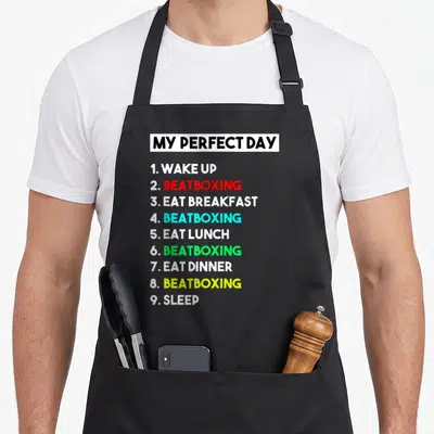 Tablier de cuisine noir avec une liste numerique en anglais et des mots beatboxing en couleurs vives sur fond gris.