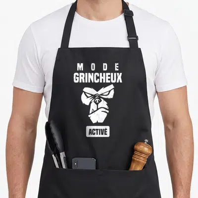 Tablier de cuisine noir avec inscription Mode grincheux activé et illustration de singe stylisée en blanc.
