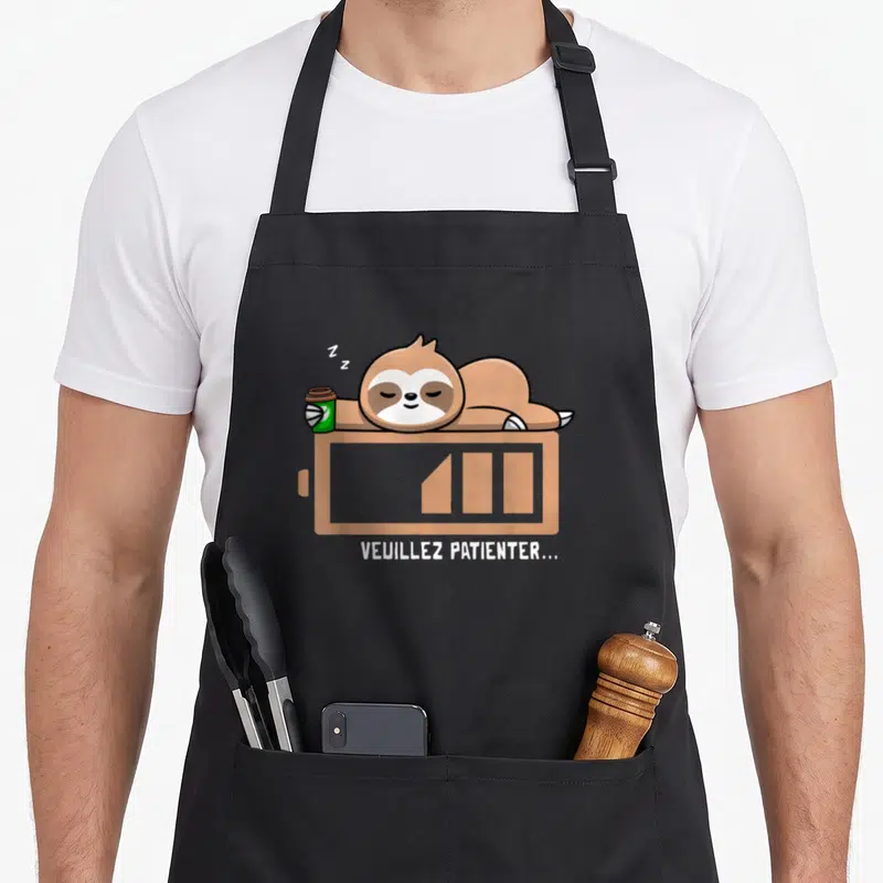 Tablier de cuisine noir avec paresseux dormant sur une icône de batterie faible verte et marron.
