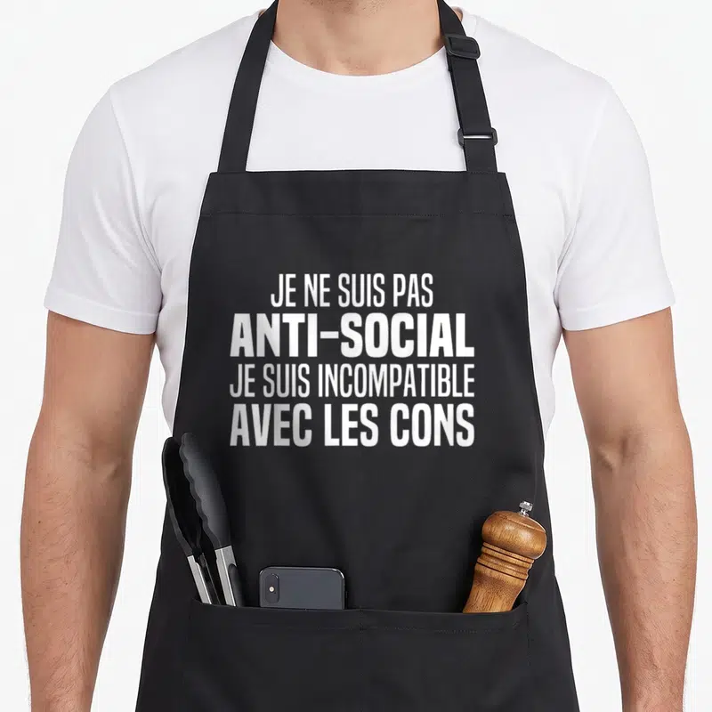 Tablier de cuisine noir avec l'inscription blanche Je ne suis pas antisocial je suis incompatible avec les cons centrée sur le devant.