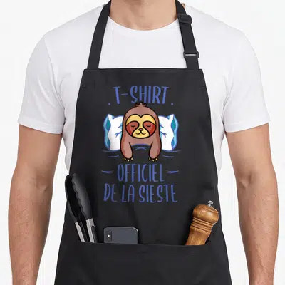 Tablier de cuisine noir avec un fourmi paresseux dormant sur un oreiller blanc et bleu.