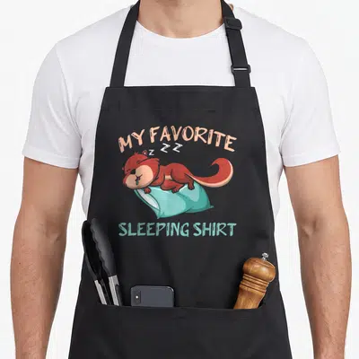 Tablier de cuisine noir avec illustration d'un écureuil rouge dormant sur un coussin bleu et le texte My Favorite Sleeping Shirt.