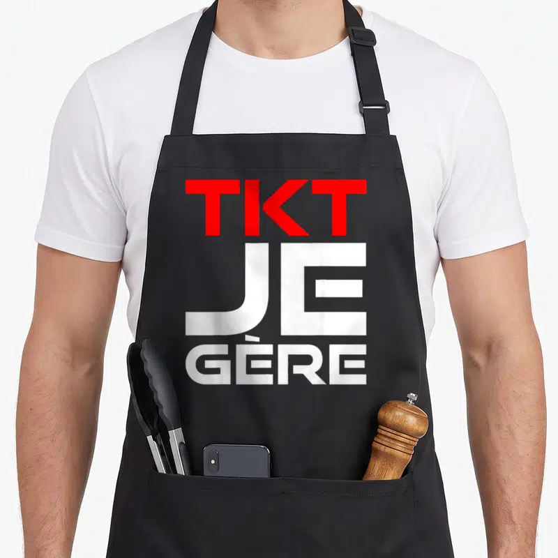 Tablier de cuisine noir avec inscription TKT Je Gère en lettres rouges et blanches stylisées.
